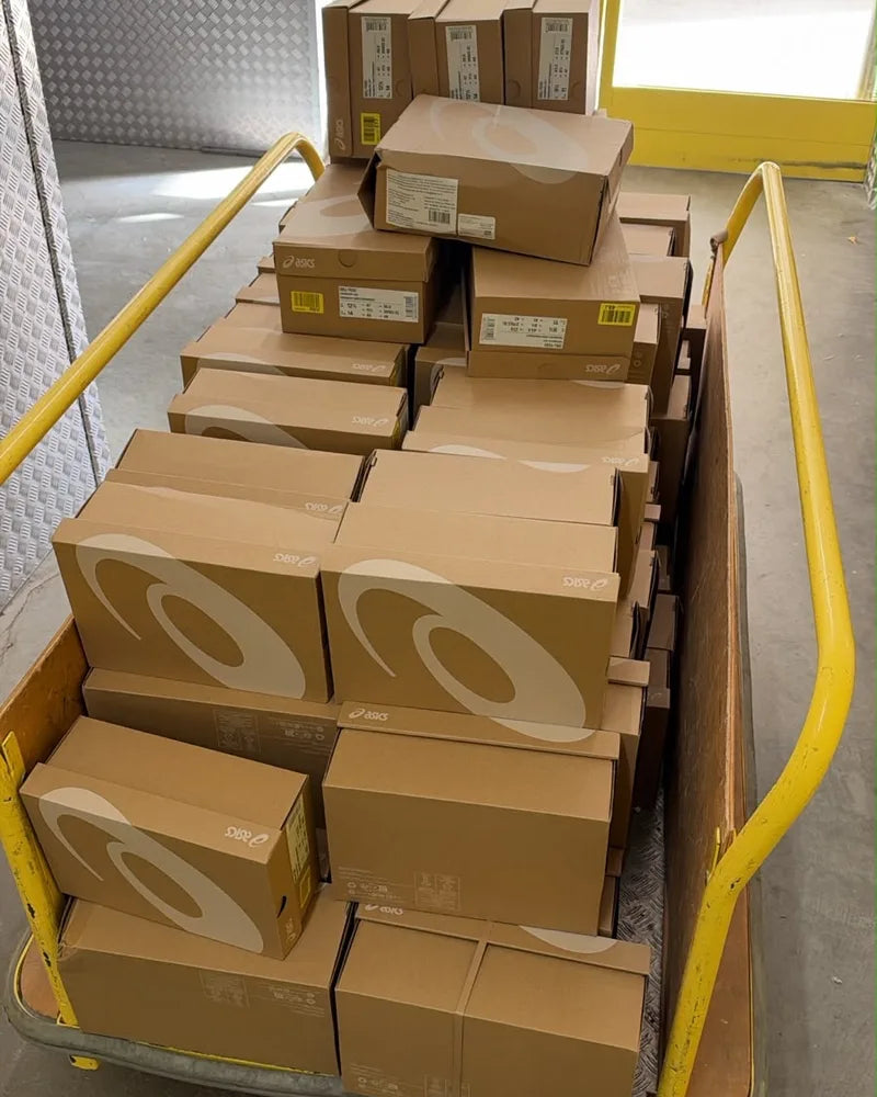 A trolley loaded with ASICS boxes